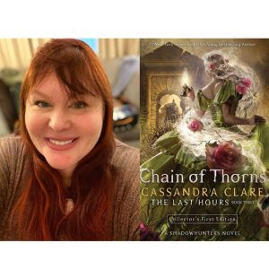 Author Cassandra Clare smiles next to her book cover, Chain of Thorns.