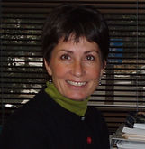 Smiling woman in black sweater poses. Message from the Director: August 2025.
